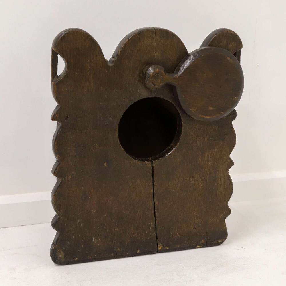 A dark brown 17th or 18th-century carved oak salt box featuring a shaped backboard with a circular hanging aperture and a sloping hinged lid. View VI