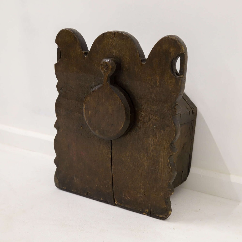 A dark brown 17th or 18th-century carved oak salt box featuring a shaped backboard with a circular hanging aperture and a sloping hinged lid. View VIII