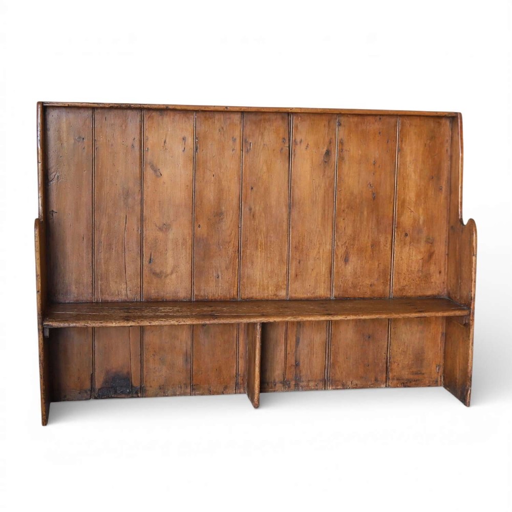 A 19th-century English country pine high-back settle bench with vertical timber panels and a warm honey brown finish.