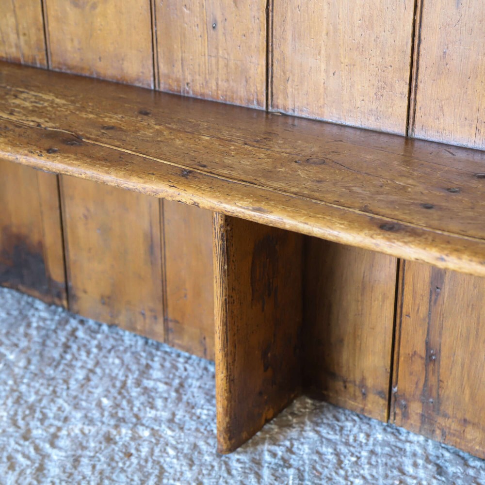 A 19th-century English country pine high-back settle bench with vertical timber panels and a warm honey brown finish. View V