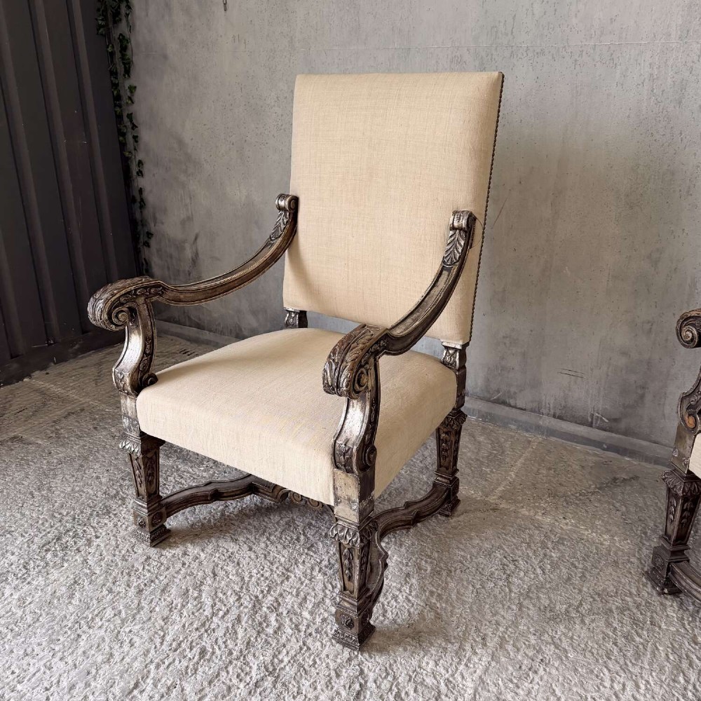 A pair of 19th-century Baroque-style throne armchairs featuring carved giltwood frames and neutral linen upholstery. View V