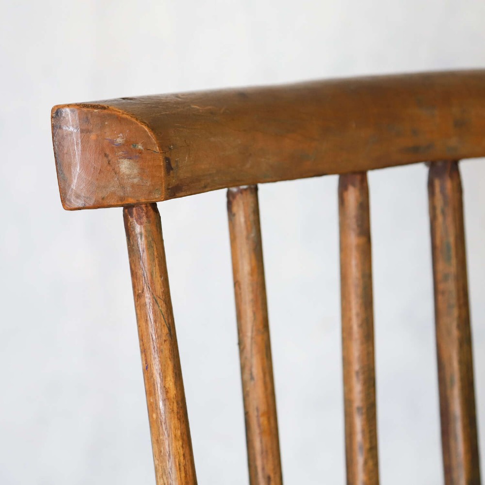 A 19th-century primitive comb-back rocking chair crafted from wood with tall back spindles, turned arm supports, and curved wooden runners. View VI