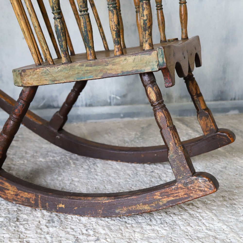 A 19th-century primitive comb-back rocking chair crafted from wood with tall back spindles, turned arm supports, and curved wooden runners. View VIII