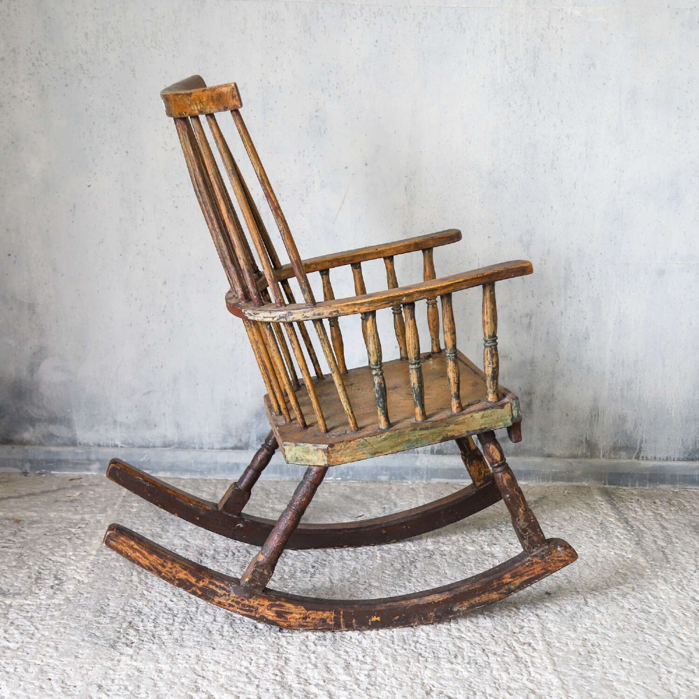 A 19th-century primitive comb-back rocking chair crafted from wood with tall back spindles, turned arm supports, and curved wooden runners. View IX