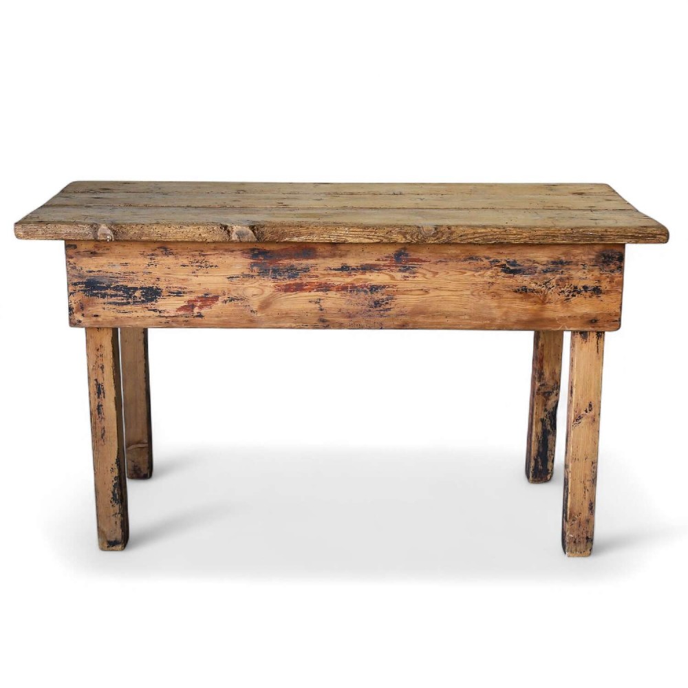 A rustic early twentieth-century Welsh pine work table featuring a thick timber plank top, deep apron, and simple straight square legs with a distressed finish.