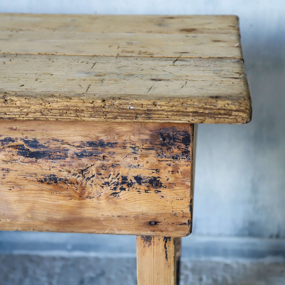 A rustic early twentieth-century Welsh pine work table featuring a thick timber plank top, deep apron, and simple straight square legs with a distressed finish. View V