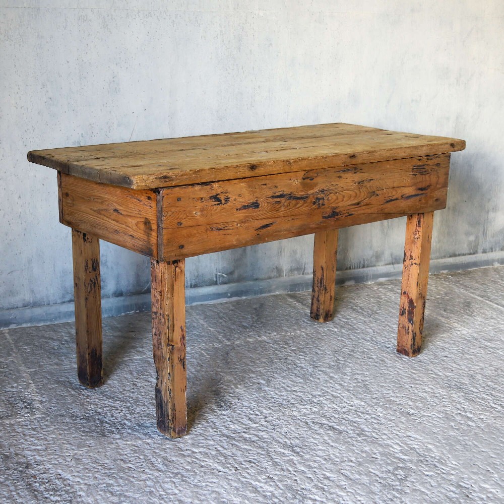 A rustic early twentieth-century Welsh pine work table featuring a thick timber plank top, deep apron, and simple straight square legs with a distressed finish. View X