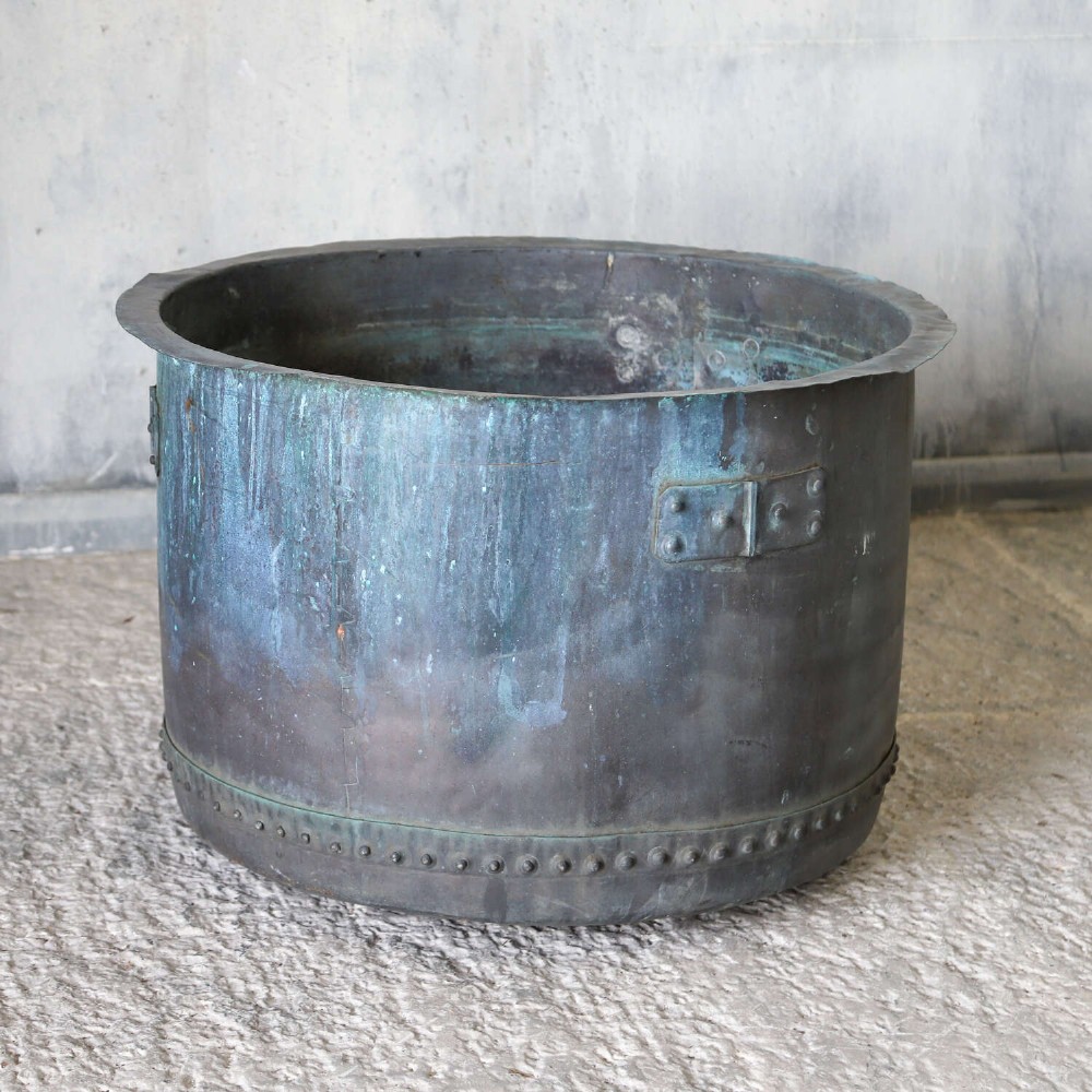 A large circular 19th-century copper tub featuring hand-riveted construction, side handles, and a blue-green verdigris patina. View II
