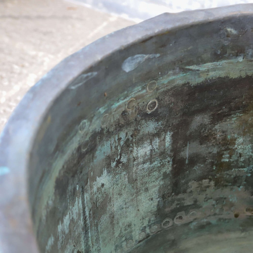 A large circular 19th-century copper tub featuring hand-riveted construction, side handles, and a blue-green verdigris patina. View V