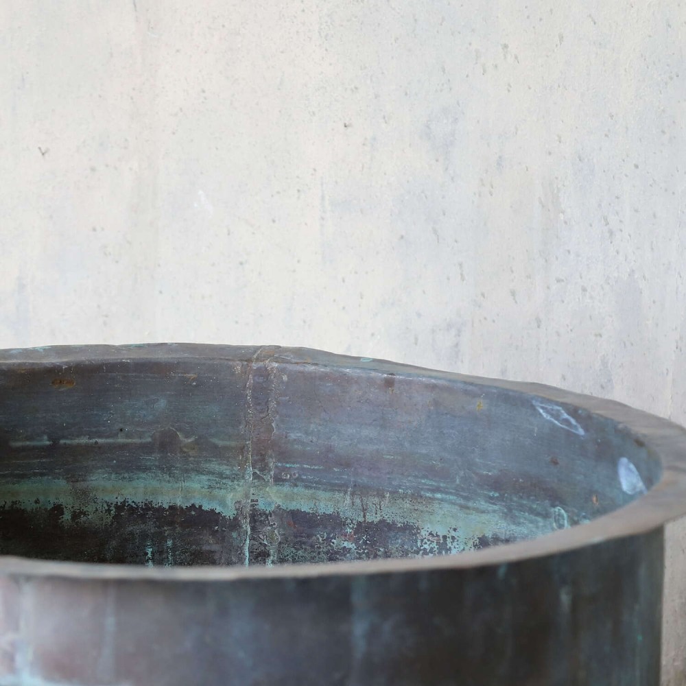 A large circular 19th-century copper tub featuring hand-riveted construction, side handles, and a blue-green verdigris patina. View IX