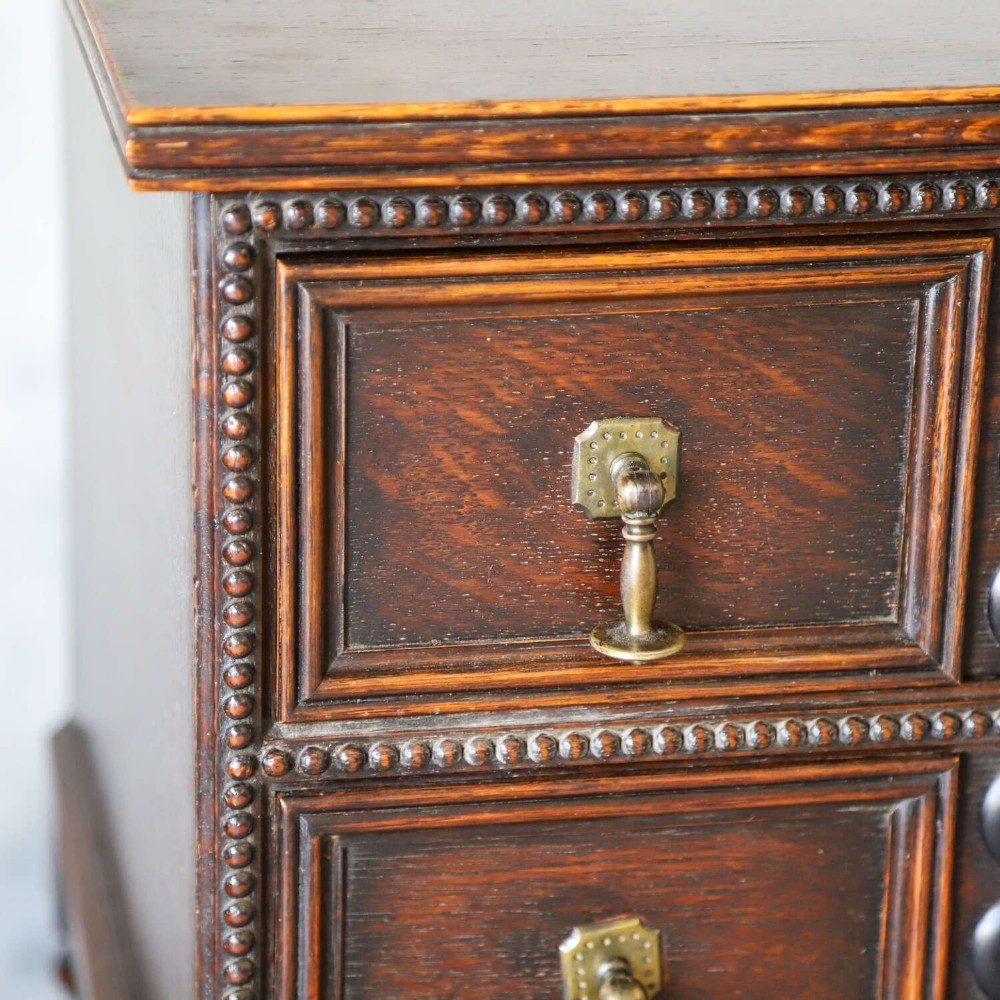 A dark oak Carolean Revival sideboard featuring two geometrically panelled drawers, intricate carving, and barley-twist legs connected by stretchers. View III