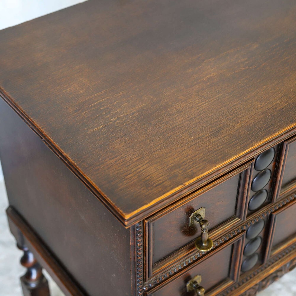 A dark oak Carolean Revival sideboard featuring two geometrically panelled drawers, intricate carving, and barley-twist legs connected by stretchers. View XI