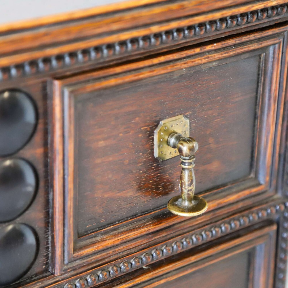 A dark oak Carolean Revival sideboard featuring two geometrically panelled drawers, intricate carving, and barley-twist legs connected by stretchers. View XIII