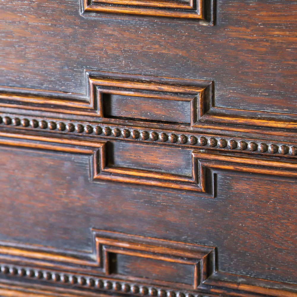 A dark oak Carolean Revival sideboard featuring two geometrically panelled drawers, intricate carving, and barley-twist legs connected by stretchers. View XIV