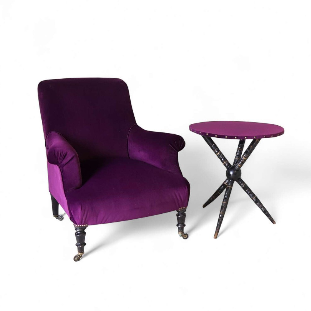 A Napoleon III armchair and matching Aesthetic Movement gypsy table upholstered in purple velvet with ebonised turned legs.