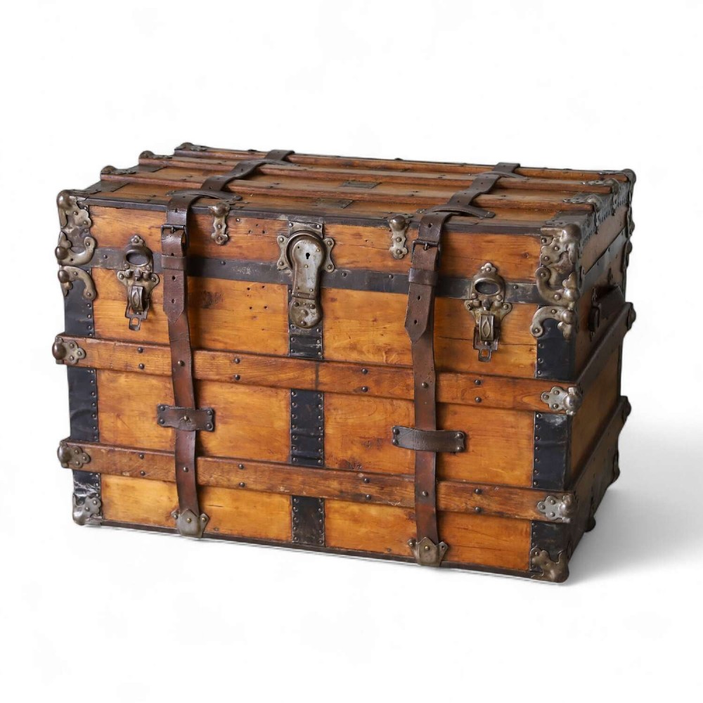A 19th-century Victorian pine travelling trunk featuring wooden battens, iron corner brackets, central lock plate, and leather securing straps.