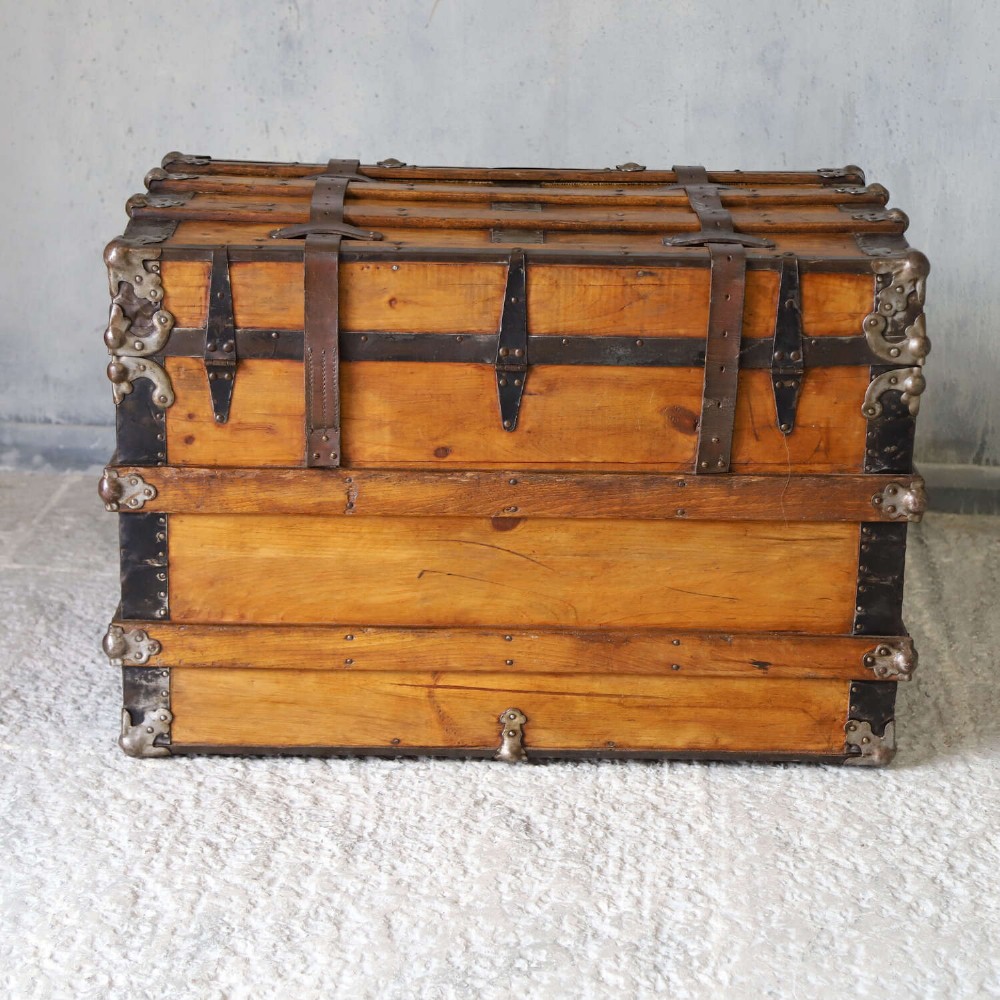 A 19th-century Victorian pine travelling trunk featuring wooden battens, iron corner brackets, central lock plate, and leather securing straps. View IV