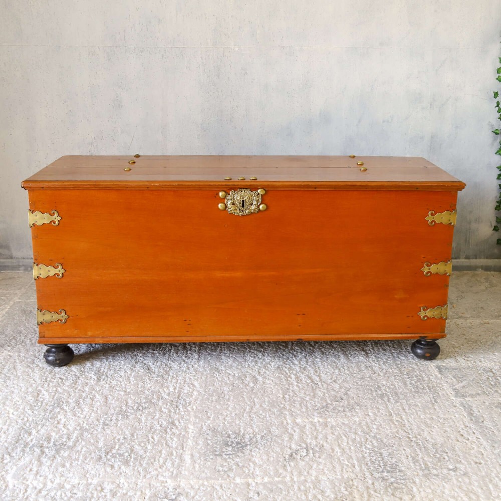 An 18th-century walnut colonial chest featuring decorative brass corner brackets, a central brass escutcheon, and dark turned feet. View II