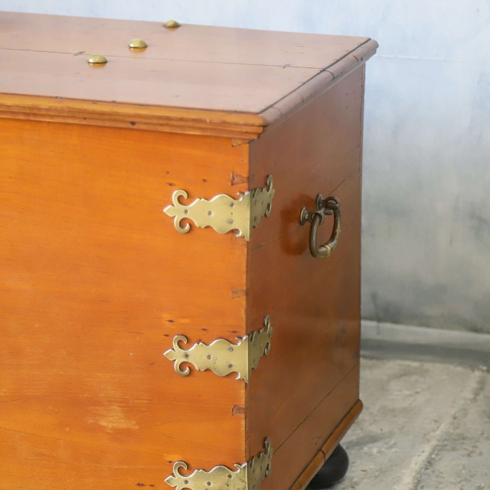 An 18th-century walnut colonial chest featuring decorative brass corner brackets, a central brass escutcheon, and dark turned feet. View III