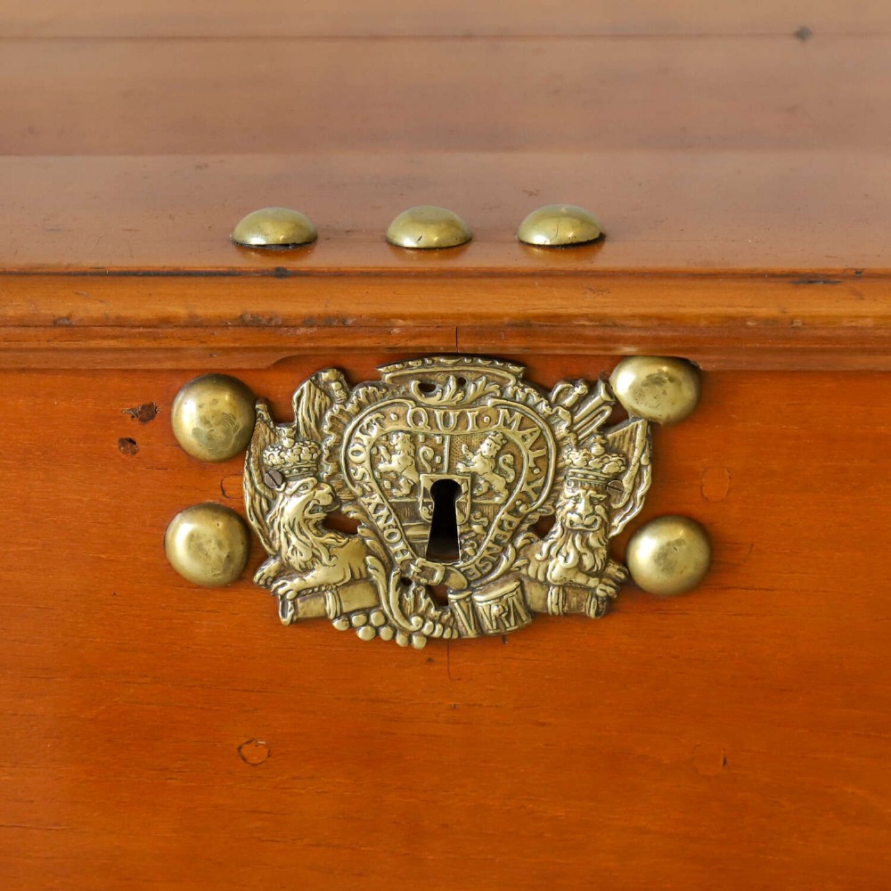An 18th-century walnut colonial chest featuring decorative brass corner brackets, a central brass escutcheon, and dark turned feet. View VI
