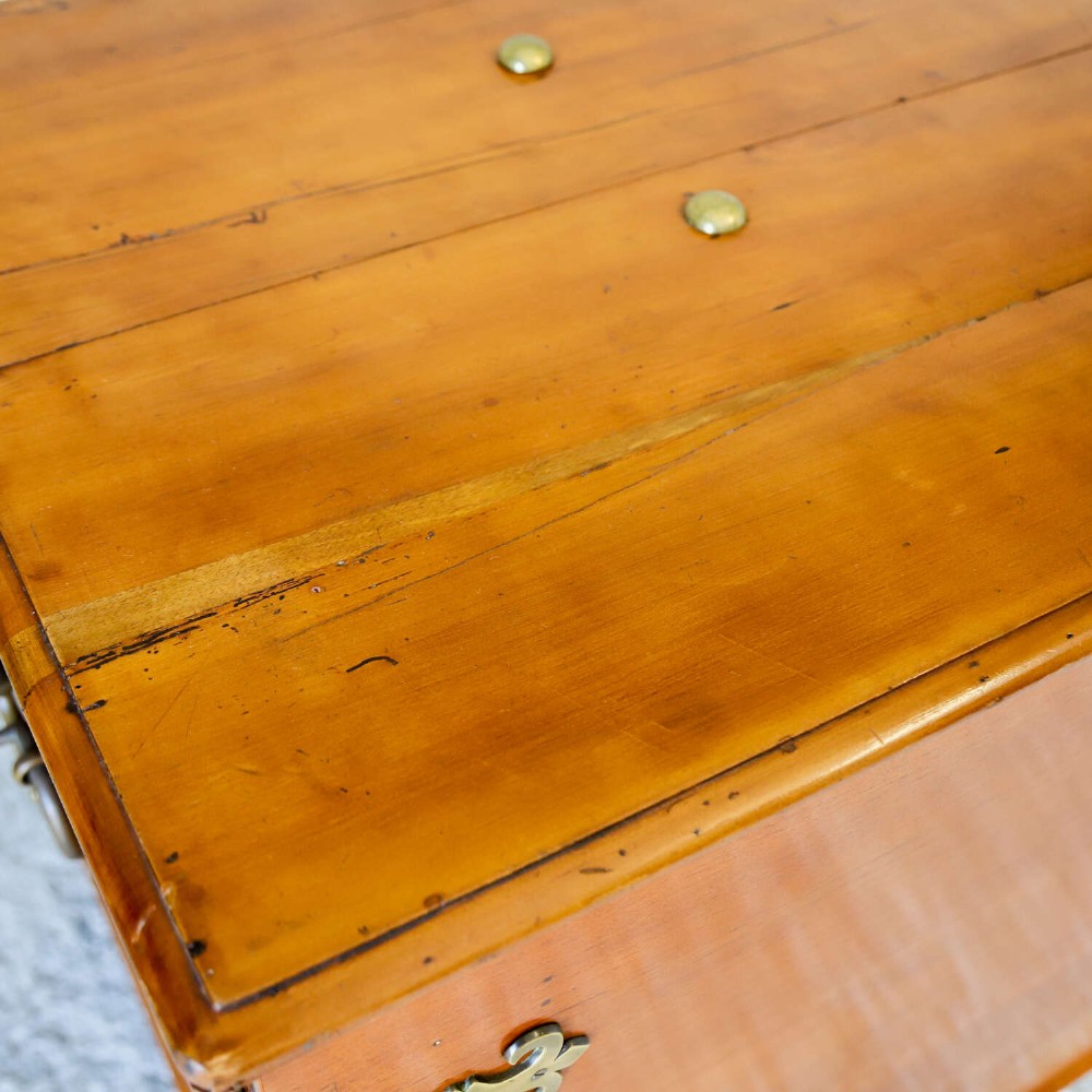 An 18th-century walnut colonial chest featuring decorative brass corner brackets, a central brass escutcheon, and dark turned feet. View XI