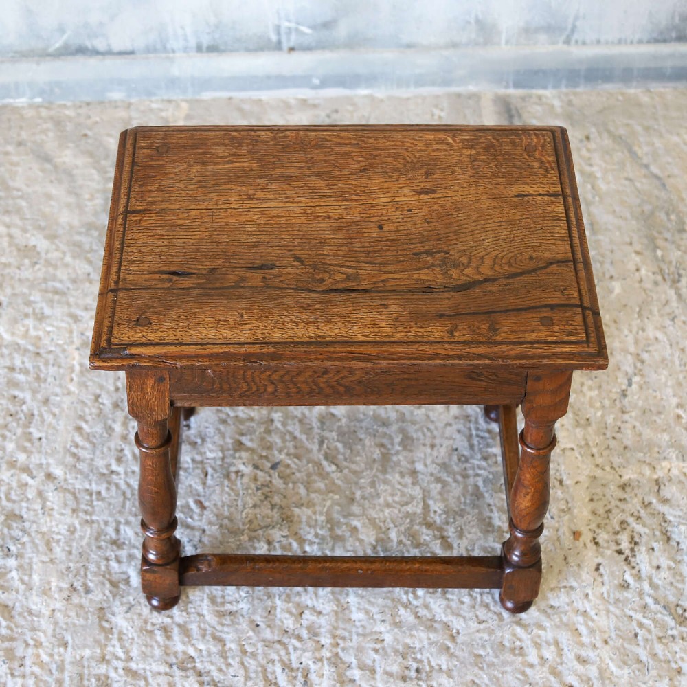 An 18th-century English Georgian oak joint stool featuring turned legs, perimeter stretchers, and a rectangular top with pegged joinery. View III