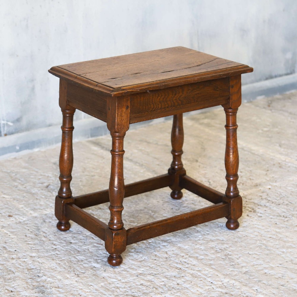 An 18th-century English Georgian oak joint stool featuring turned legs, perimeter stretchers, and a rectangular top with pegged joinery. View V