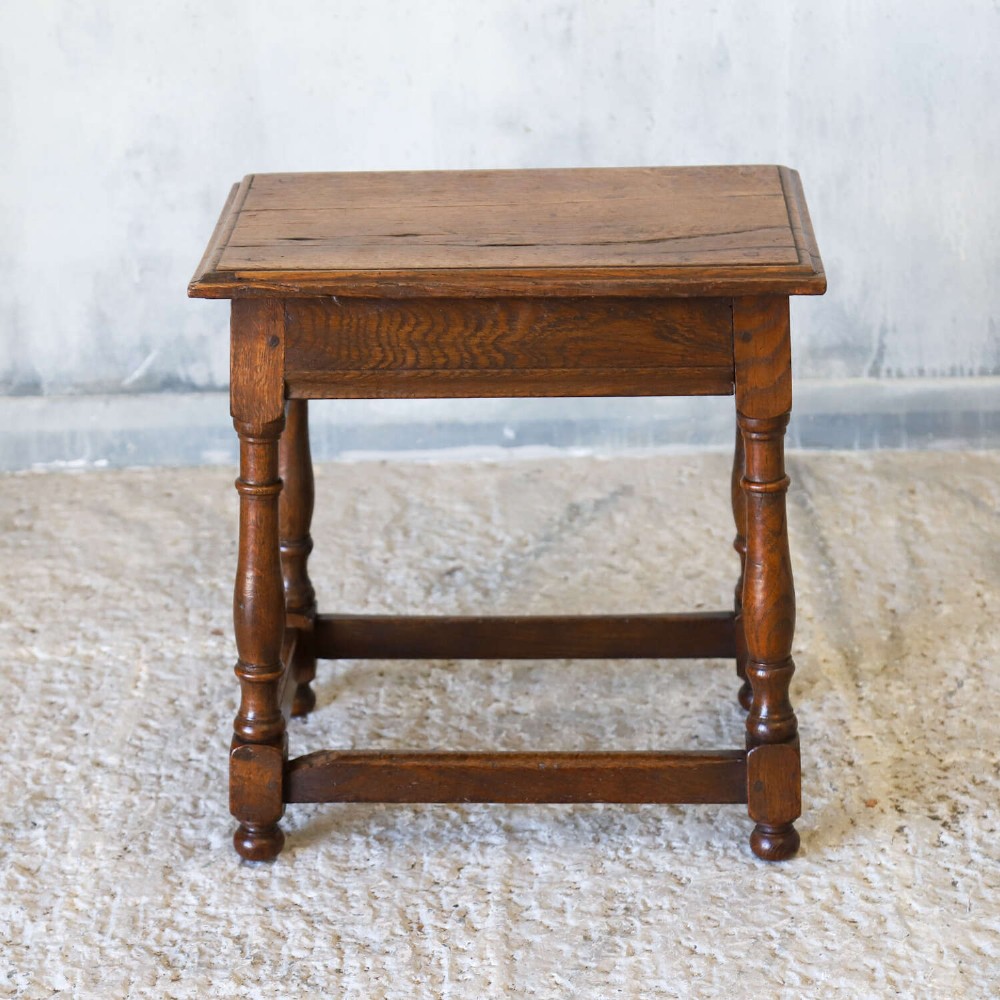 An 18th-century English Georgian oak joint stool featuring turned legs, perimeter stretchers, and a rectangular top with pegged joinery. View VI