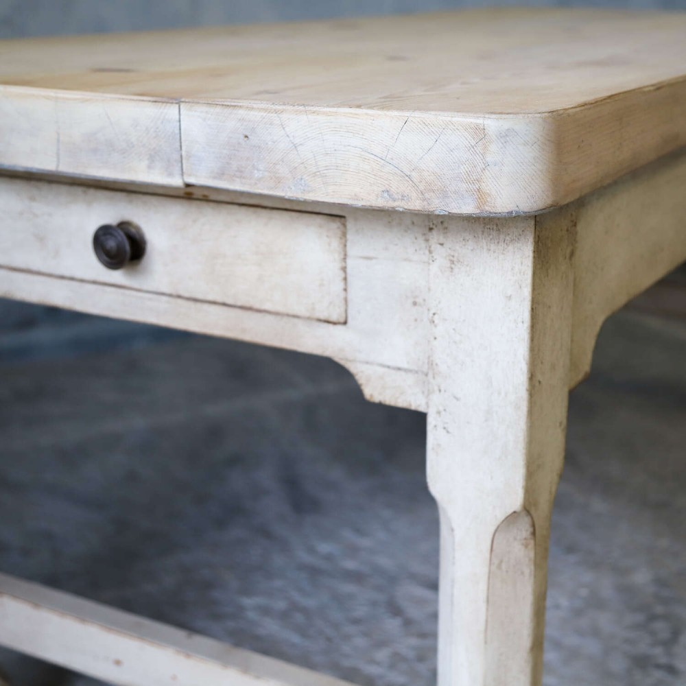 A 19th-century English country house prep table featuring a thick natural timber top, an off-white painted wooden base, a side drawer, and low stretchers. View XII