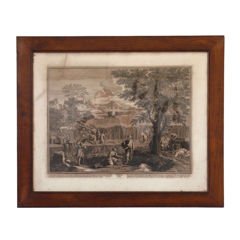 A framed monochrome engraving depicting a classical harvest landscape scene with figures working in a field beneath trees, enclosed in a dark wood frame.