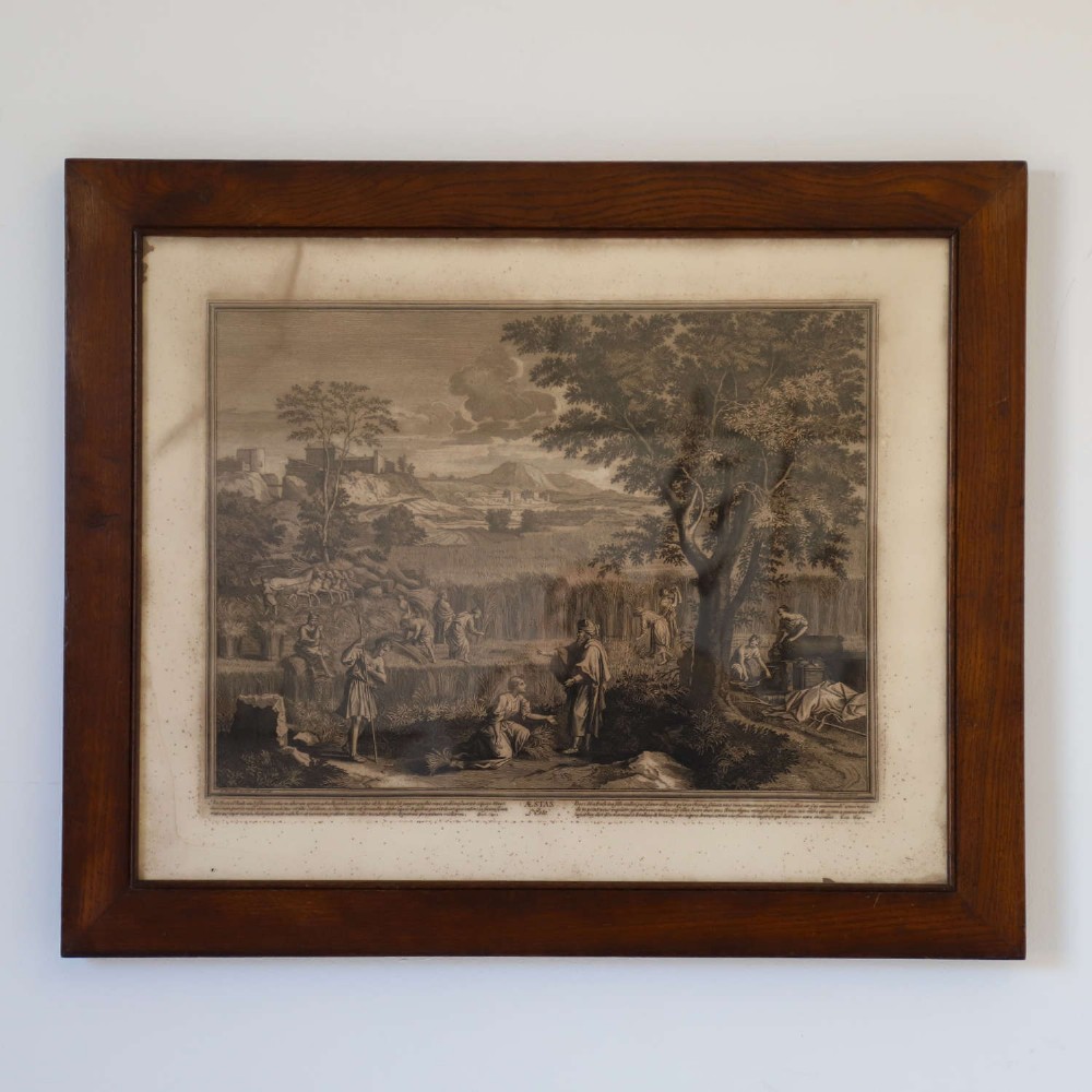 A framed monochrome engraving depicting a classical harvest landscape scene with figures working in a field beneath trees, enclosed in a dark wood frame. View II