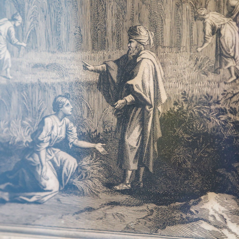 A framed monochrome engraving depicting a classical harvest landscape scene with figures working in a field beneath trees, enclosed in a dark wood frame. View IX