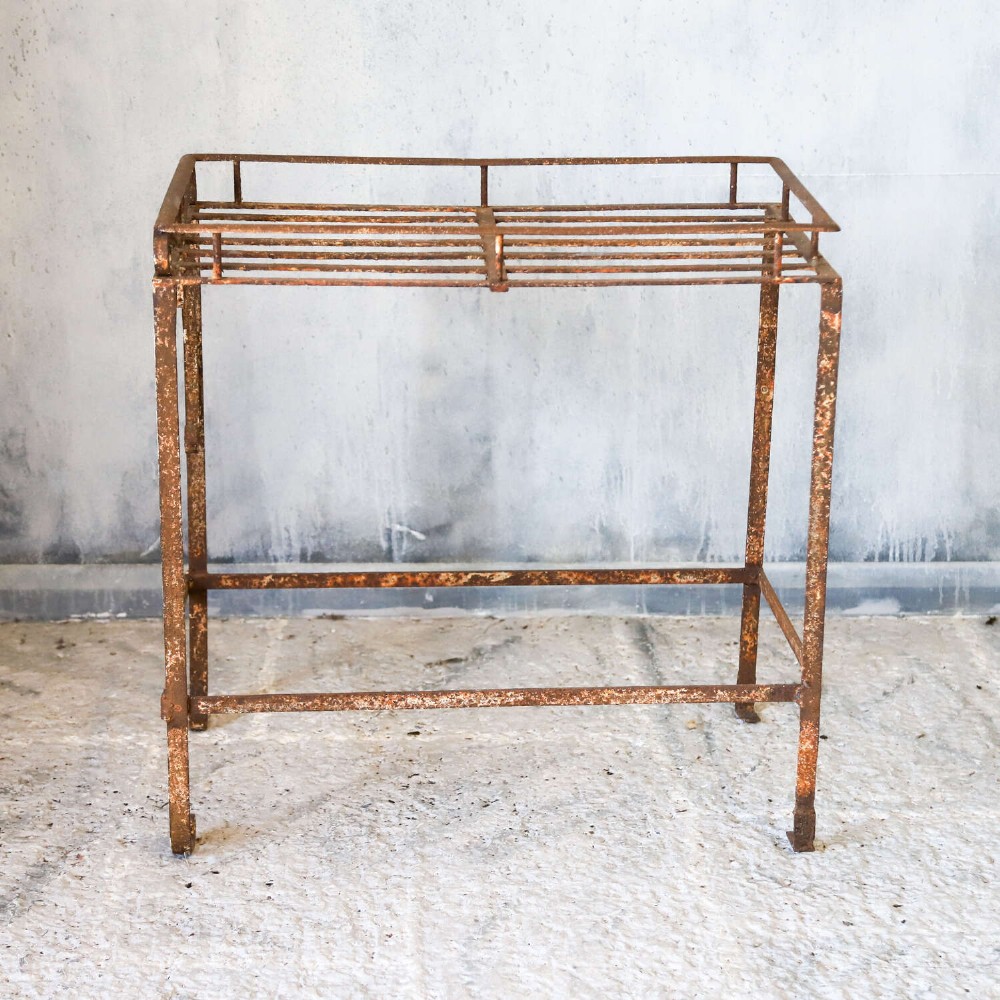 A rectangular wrought iron garden rack with a slatted top, decorative side scrollwork, and a weathered brown finish. View III