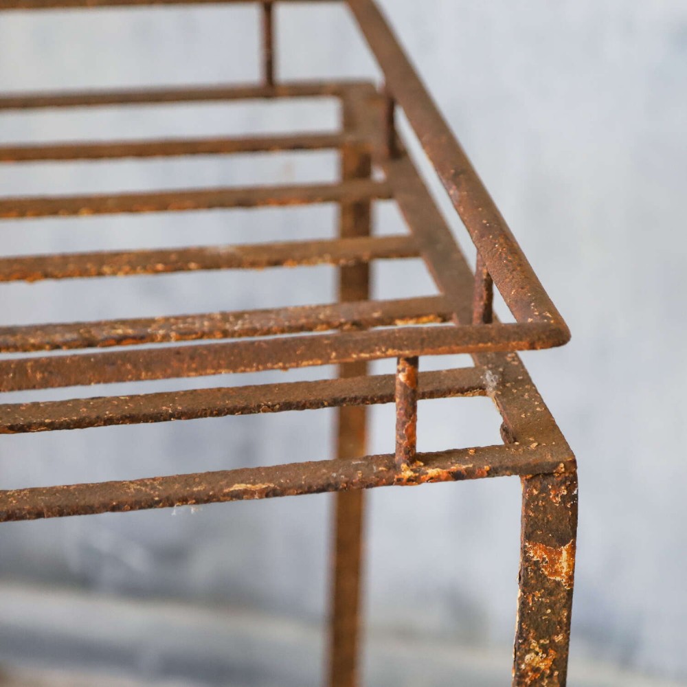 A rectangular wrought iron garden rack with a slatted top, decorative side scrollwork, and a weathered brown finish. View VIII