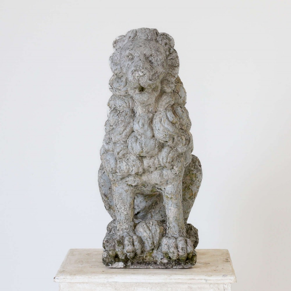 A weathered composite stone statue depicting a seated lion with a distressed, flaking grey paint finish. View II