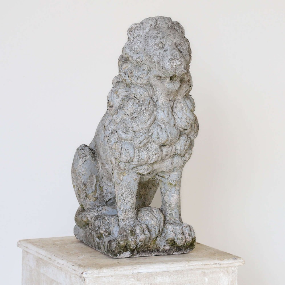 A weathered composite stone statue depicting a seated lion with a distressed, flaking grey paint finish. View III