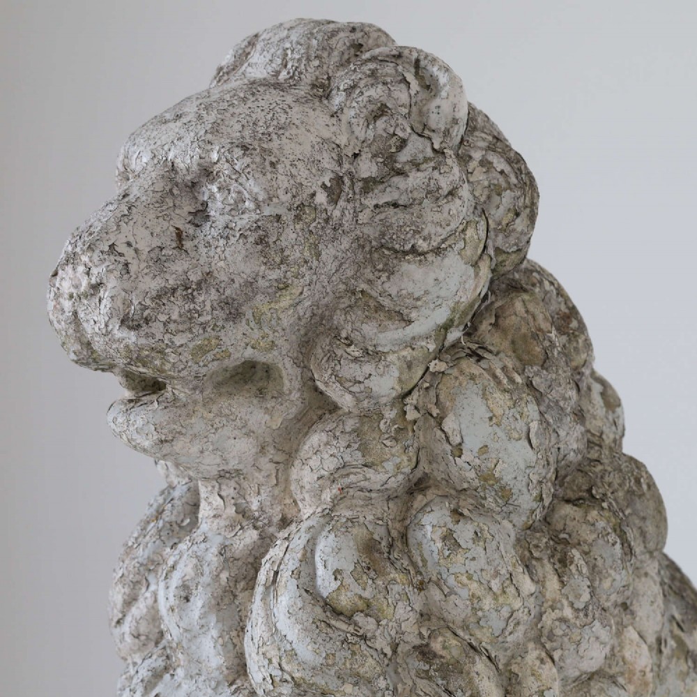 A weathered composite stone statue depicting a seated lion with a distressed, flaking grey paint finish. View VI