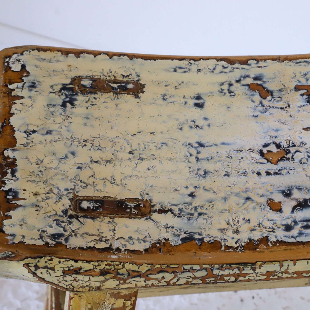 An antique Chinese elm stool featuring a slightly curved seat and a heavily distressed yellow lacquered finish over four splayed legs with horizontal stretchers. View II