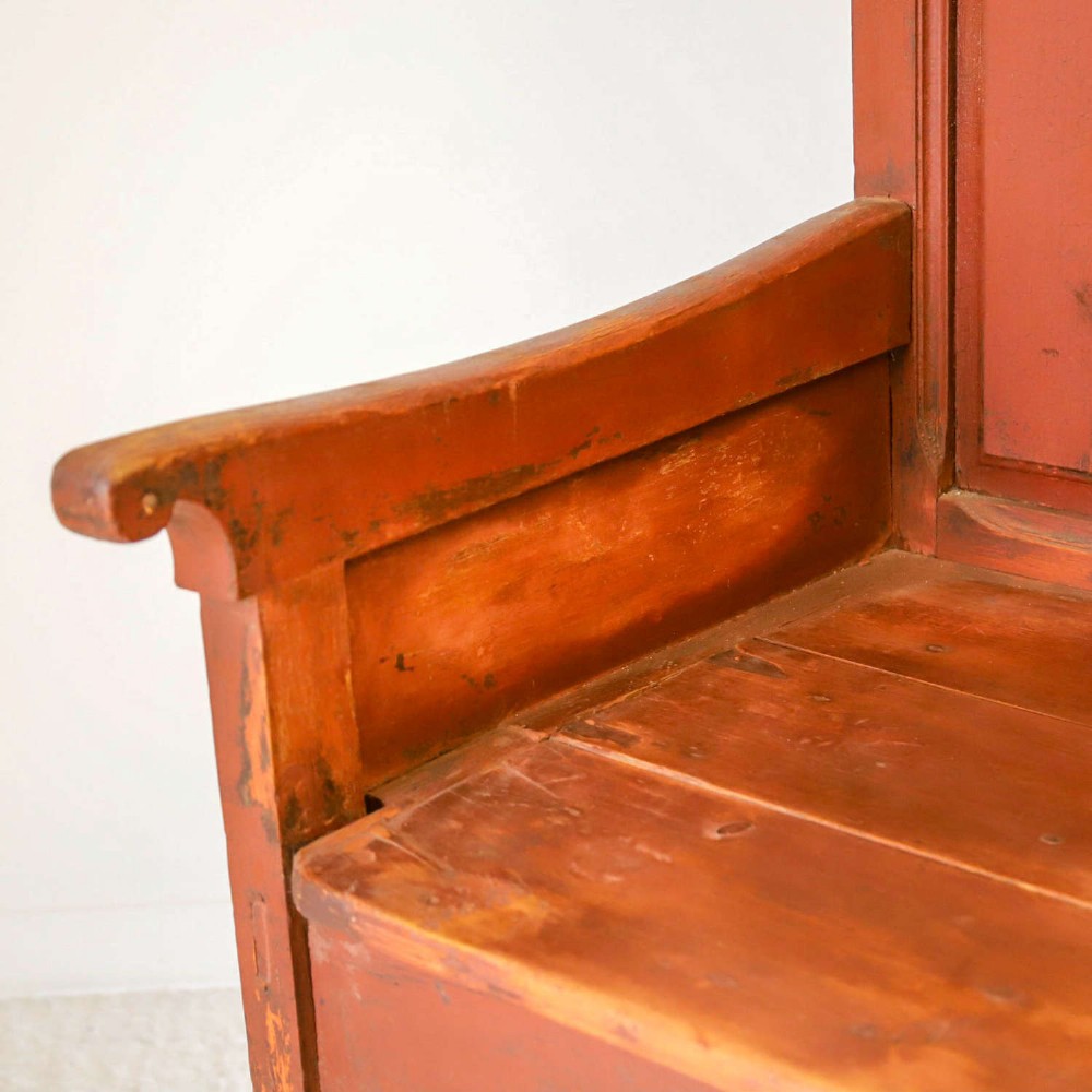 A late nineteenth-century Spanish wooden settle bench with a terracotta red painted frame, tall panelled backrest, shaped apron, and a natural timber seat. View VI