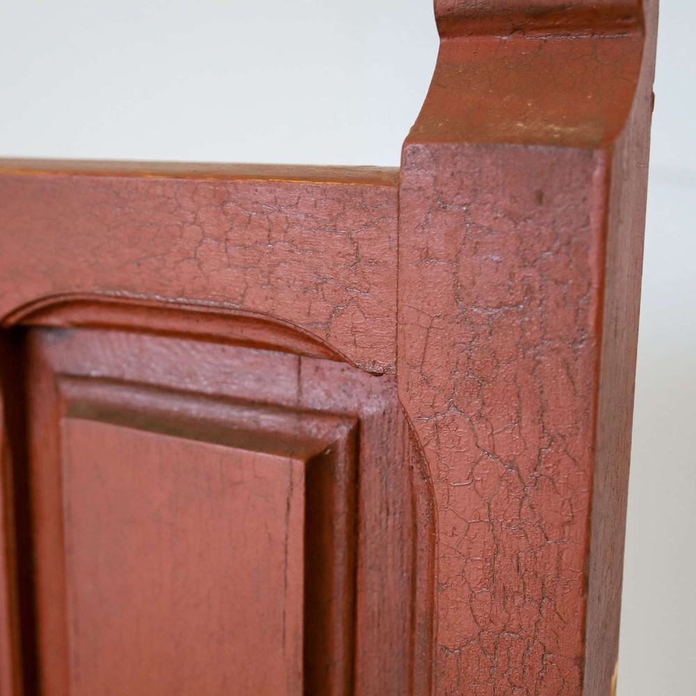 A late nineteenth-century Spanish wooden settle bench with a terracotta red painted frame, tall panelled backrest, shaped apron, and a natural timber seat. View XII