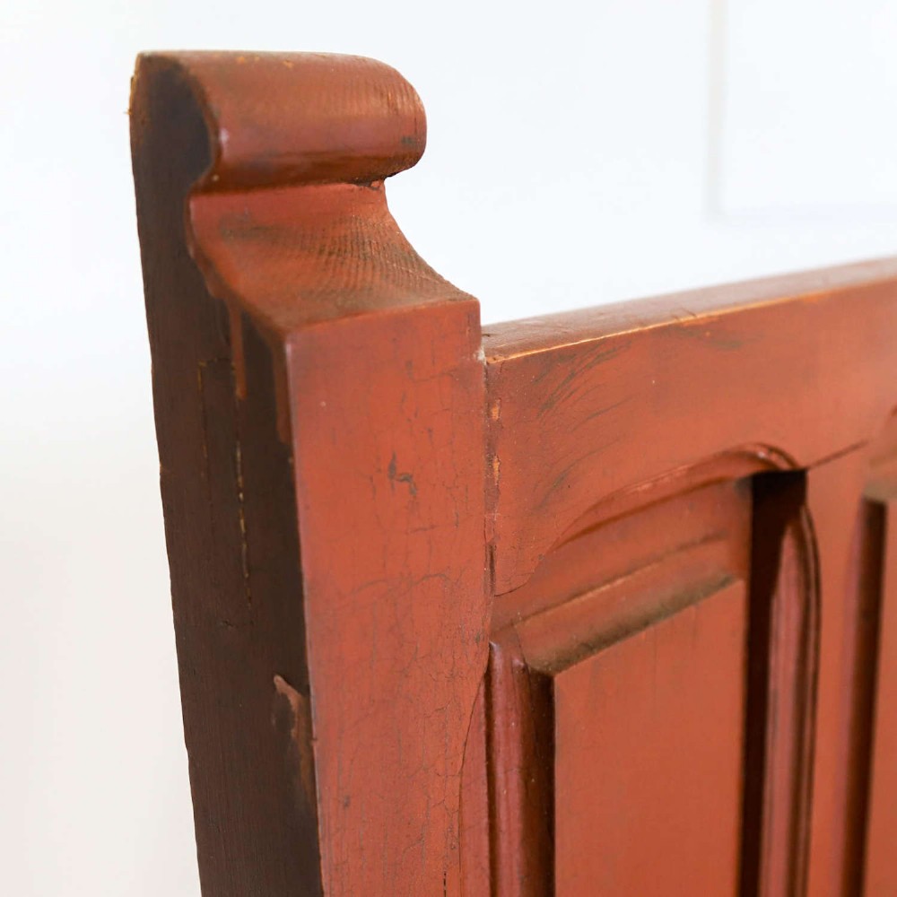 A late nineteenth-century Spanish wooden settle bench with a terracotta red painted frame, tall panelled backrest, shaped apron, and a natural timber seat. View XIII