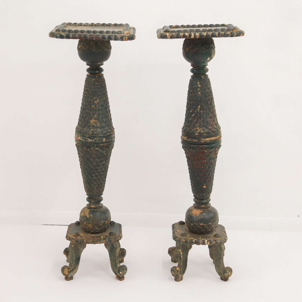A pair of carved wooden torcheres featuring fish-scale carved baluster columns, square top platforms with beaded borders, scrolled feet, and distressed original green paint. View II