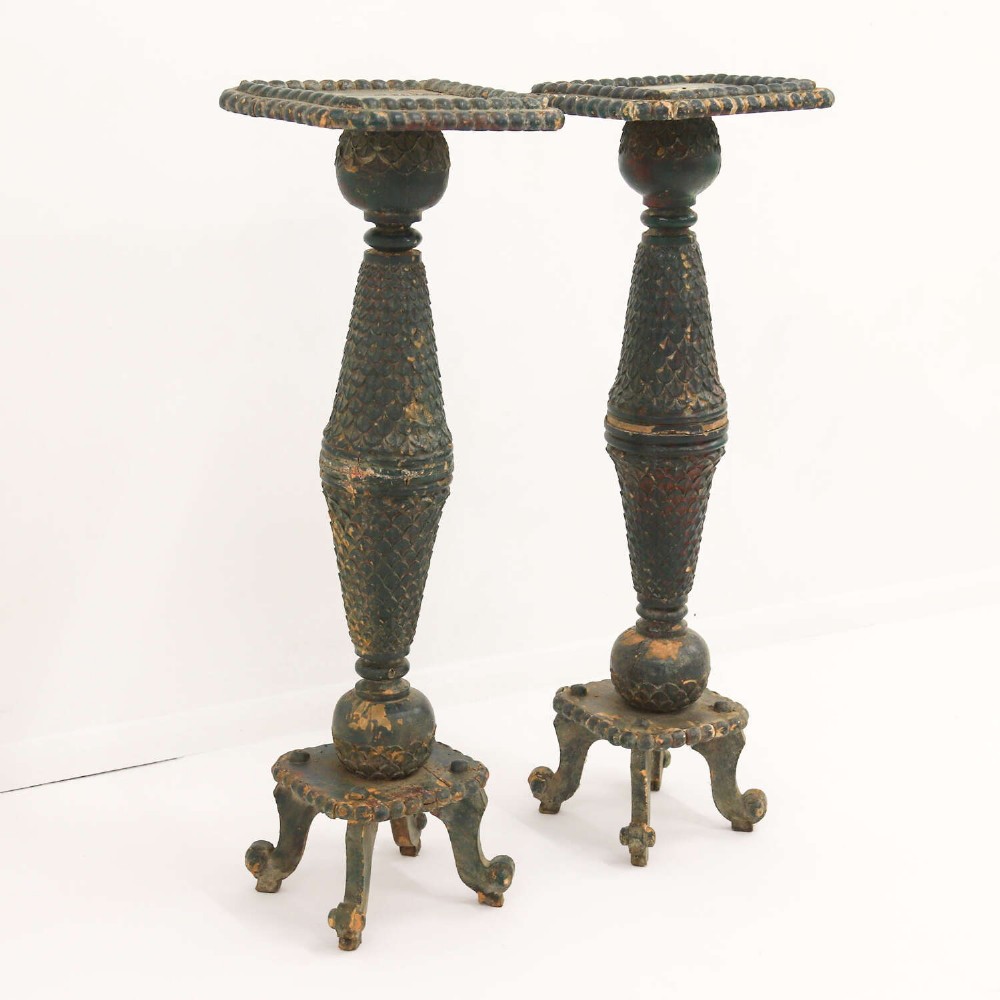 A pair of carved wooden torcheres featuring fish-scale carved baluster columns, square top platforms with beaded borders, scrolled feet, and distressed original green paint. View IV