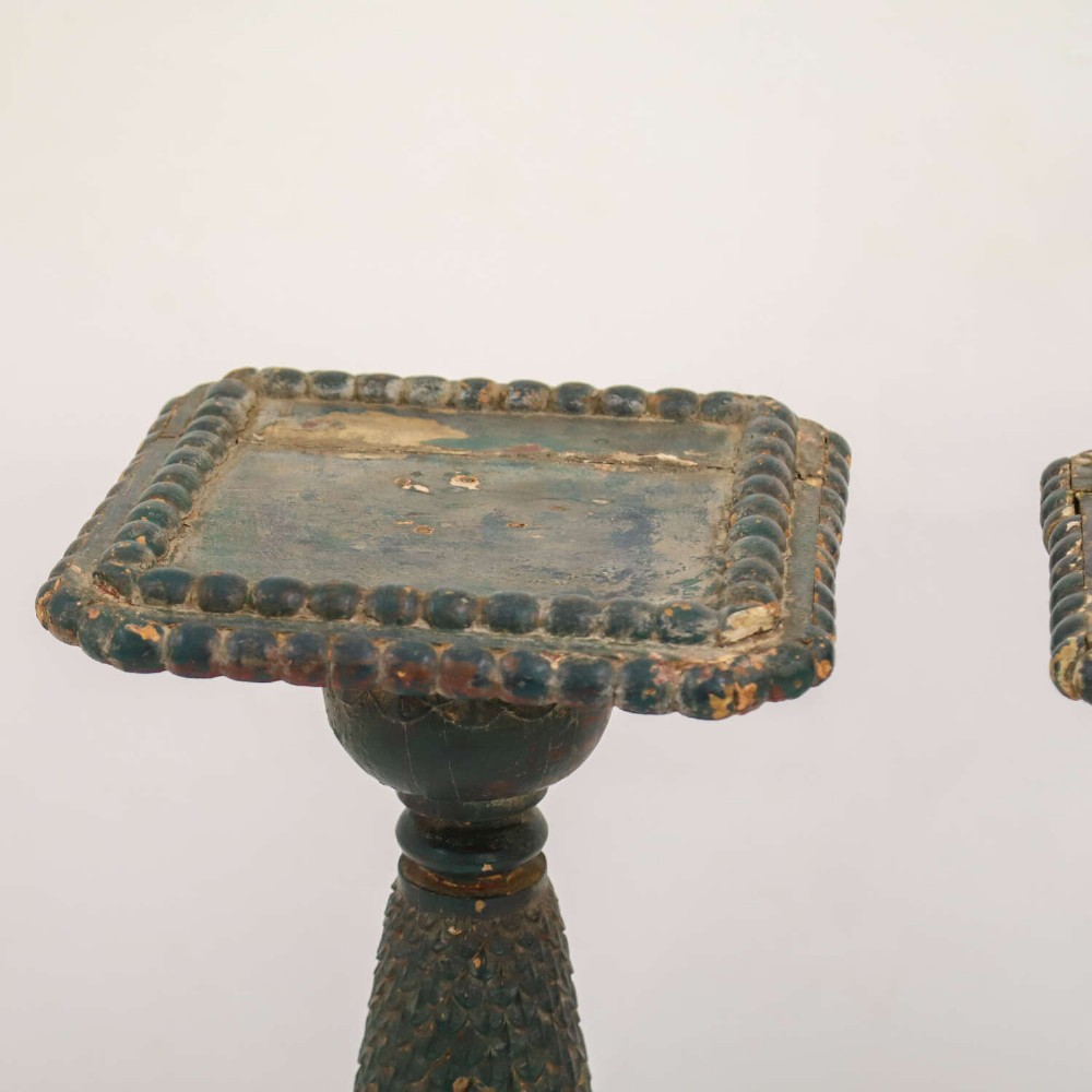 A pair of carved wooden torcheres featuring fish-scale carved baluster columns, square top platforms with beaded borders, scrolled feet, and distressed original green paint. View V