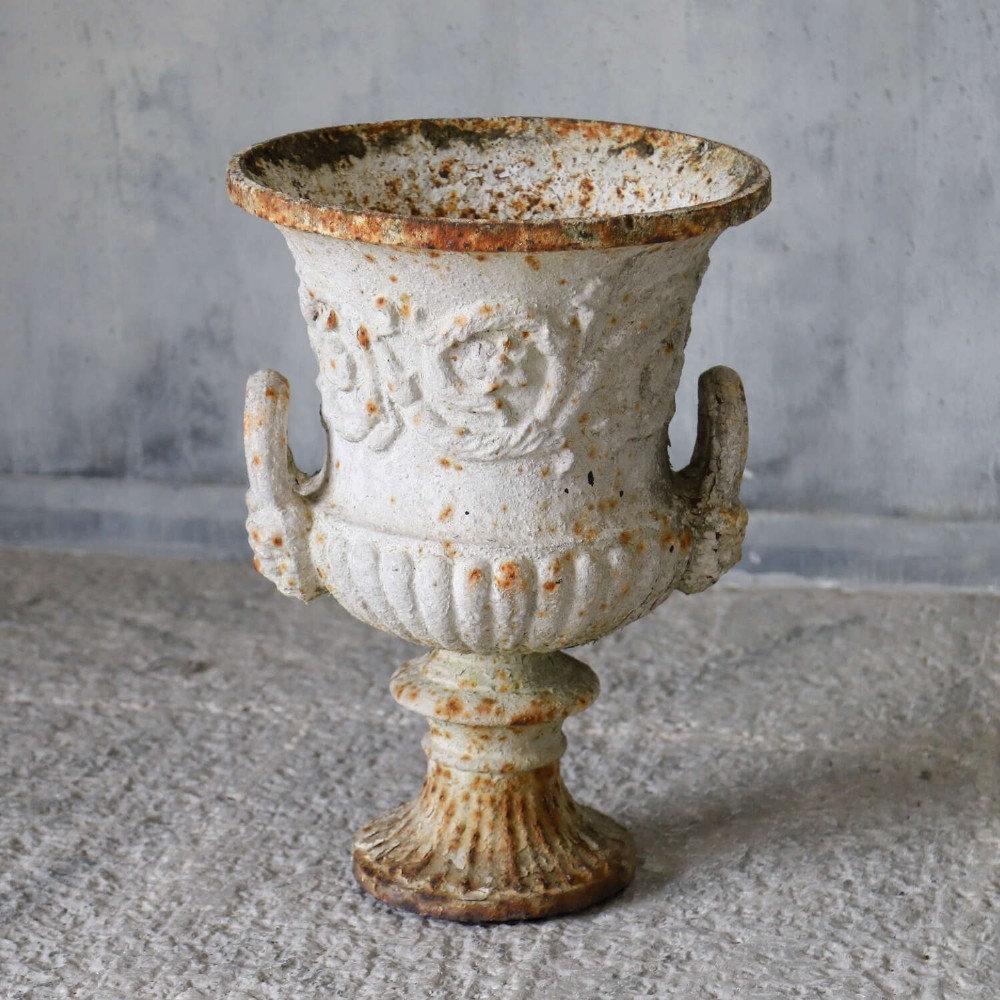 A Victorian weathered white cast iron Campana urn with twin loop handles, floral relief moulding, and surface rust. View II