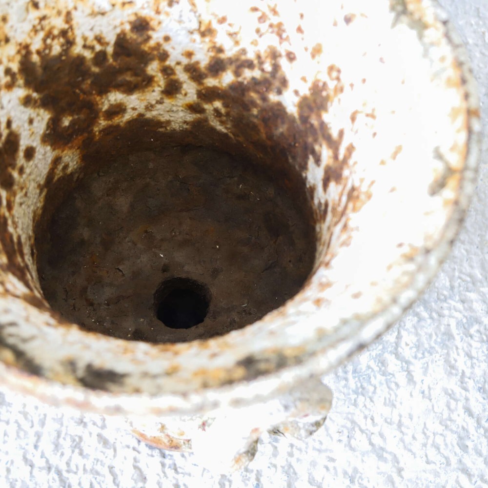 A Victorian weathered white cast iron Campana urn with twin loop handles, floral relief moulding, and surface rust. View VIII