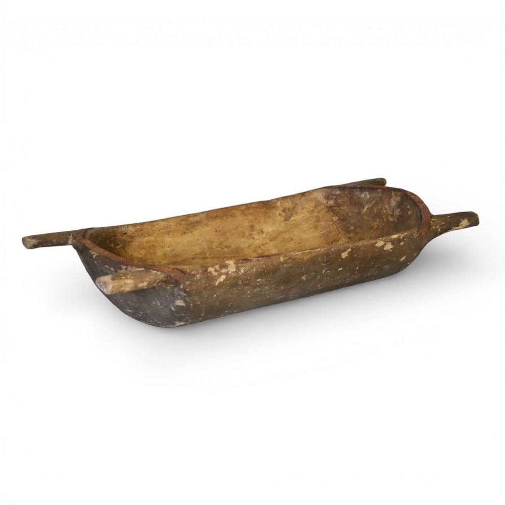 A hand-carved 19th-century French wooden dough trough with integrated handles and a weathered surface.