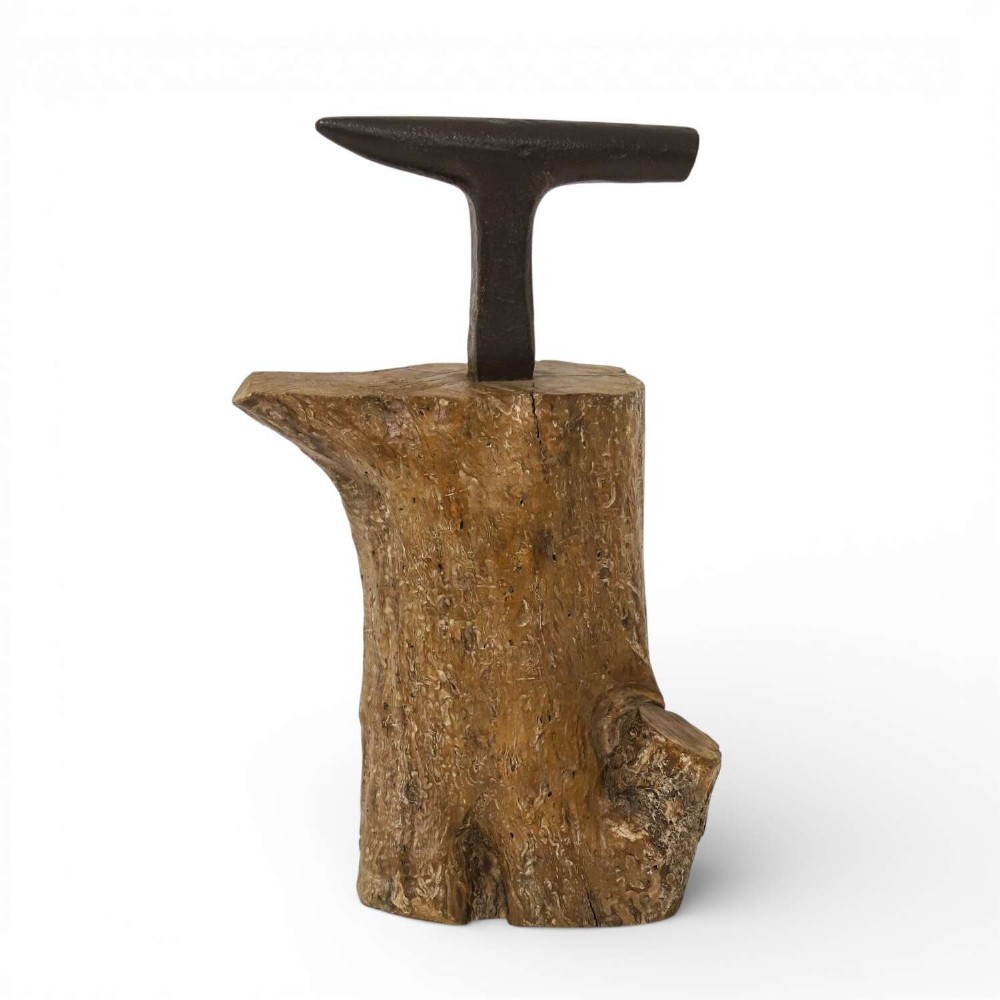 A nineteenth-century T-shaped wrought iron farriers anvil mounted into a natural carved fruitwood log trunk.