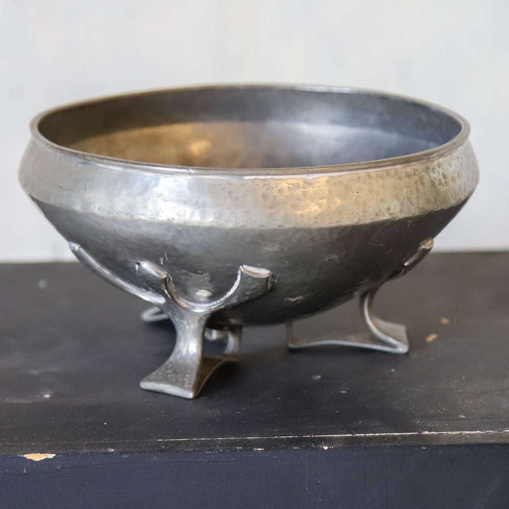 A hand-hammered grey pewter bowl featuring an inverted conical shape supported by stylised organic three-point legs. View II