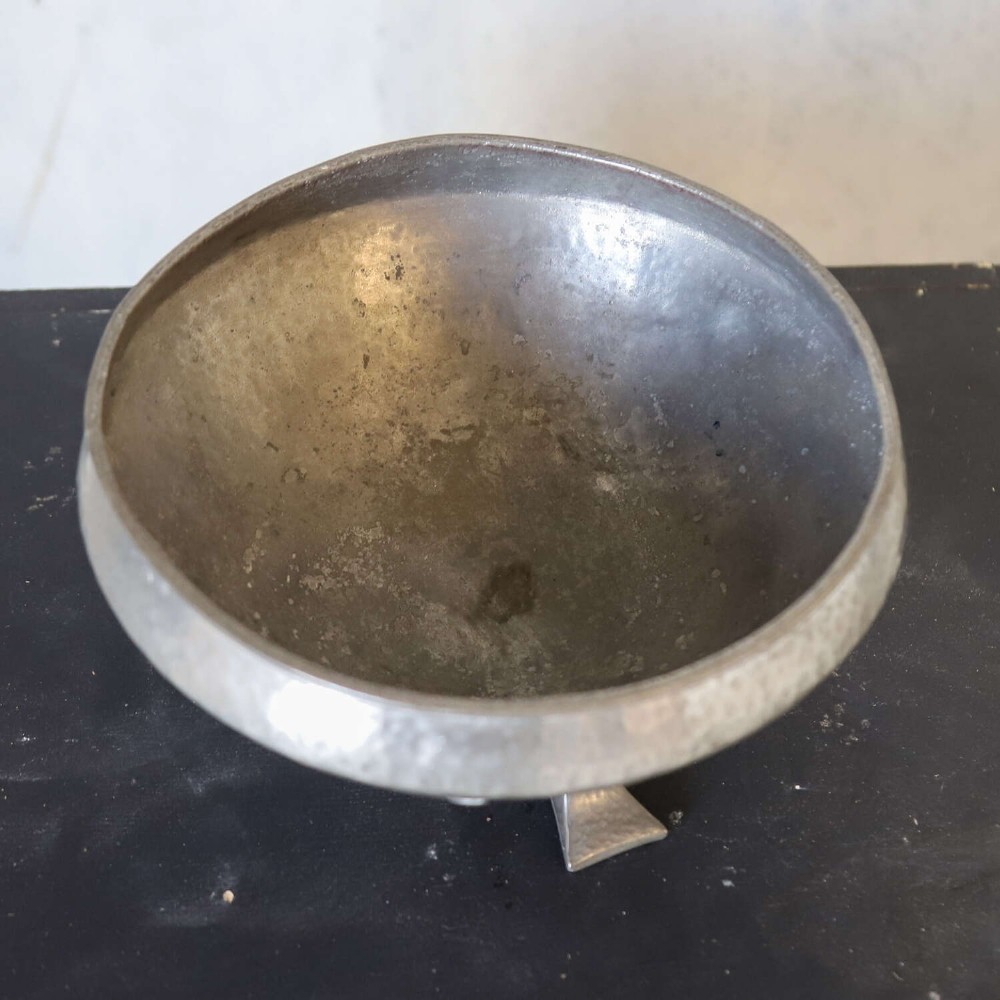 A hand-hammered grey pewter bowl featuring an inverted conical shape supported by stylised organic three-point legs. View V